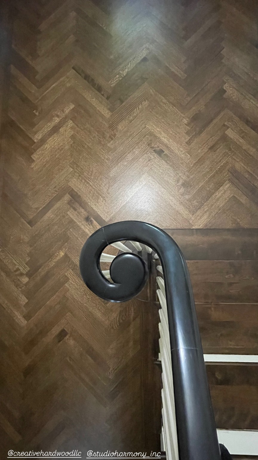 Dark herringbone landing at stair with curved handrail